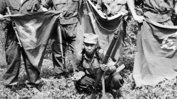 Men of a contact section of a patrol from the Cameronians (Scottish Rifles) displaying flags and caps taken from communist guerrillas after attacking their camp during the Malayan Emergency.